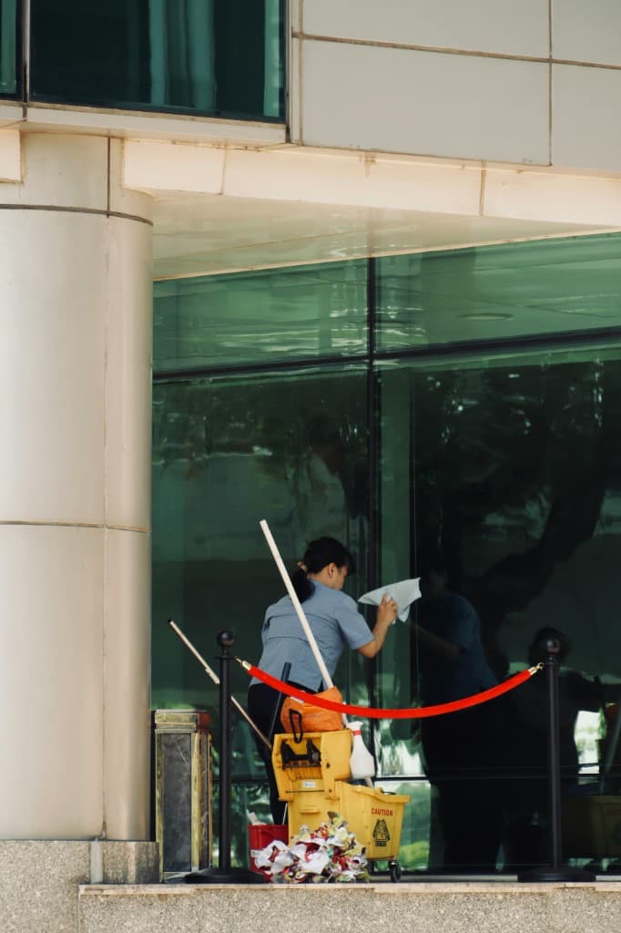 Commercial window cleaner servicing large office building glass with professional equipment