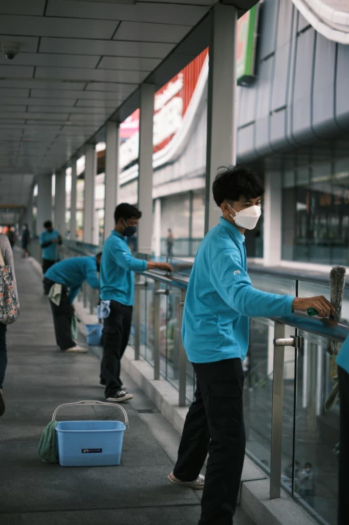 Uniformed commercial cleaning crew maintaining a modern office walkway